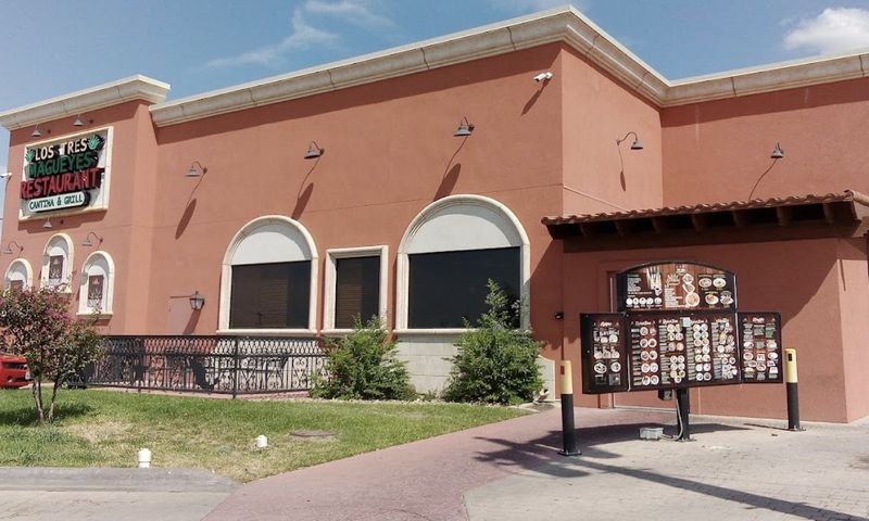 The side of the restaurant building in daylight, with the menu boards by the drive-through.